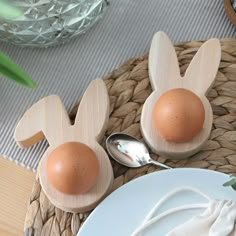 two wooden eggs in the shape of bunny ears on a plate next to a spoon