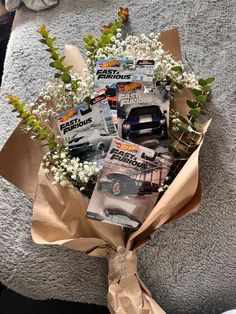 a bouquet of flowers is wrapped in brown paper and sits on the ground next to a car