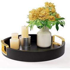 a vase with yellow flowers and candles in it on a black tray next to some candles