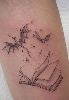 an open book with flying birds and stars on it's cover - up tattoo