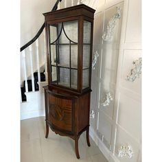 a wooden cabinet sitting in the corner of a room next to a stair case with glass doors