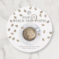 a cup of coffee on top of a white plate with nuts around it and the words pop it when she pops