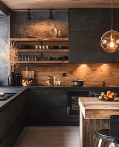 a kitchen with black cabinets and wooden counter tops is lit by pendant lights that hang from the ceiling