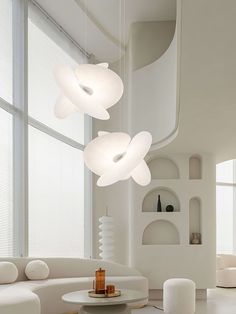 a living room filled with white furniture and large round lights hanging from the ceiling above