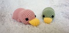 two small crocheted stuffed animals laying on top of a white blanket next to each other