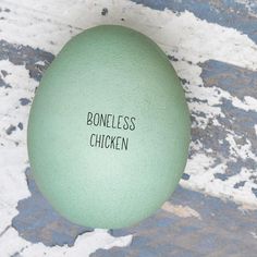 an egg with the word boneless chicken written on it's side sitting in front of a cracked surface