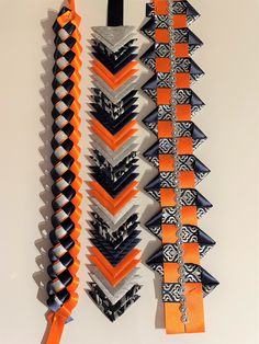 an assortment of orange, black and white decorative items hanging on a wall with ribbons