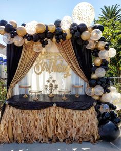 a black and gold birthday party setup with balloons, streamers, tablecloths and decorations