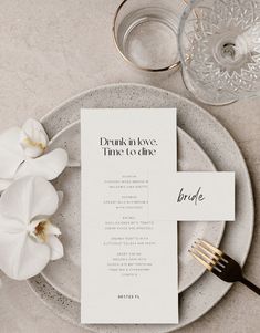 a place setting with white flowers and silverware on the table, including a menu card