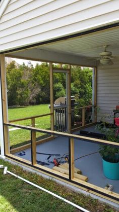 a screened porch with potted plants on the deck