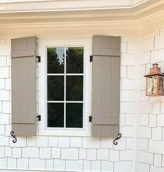 a white brick house with two windows and shutters