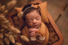 a newborn baby is wrapped up in a brown blanket with her hands under her chin