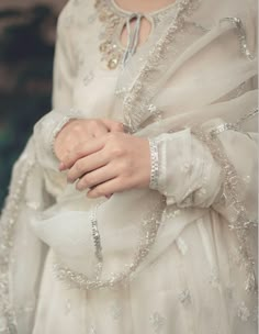 a close up of a person wearing a white dress and holding their hands on her chest