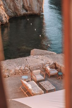 some chairs and tables by the water