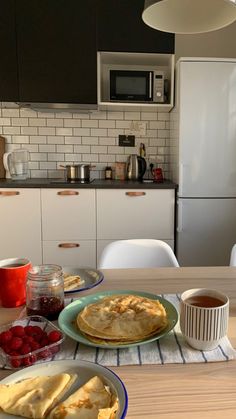 the breakfast is ready to be eaten on the table in the kitchen, with coffee and crepes