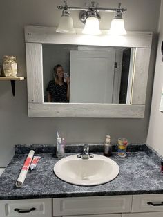 a woman taking a selfie in the bathroom mirror