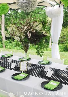 the table is set with black and white napkins, green place settings, and a chandelier