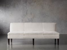 a white couch sitting on top of a hard wood floor next to a gray wall