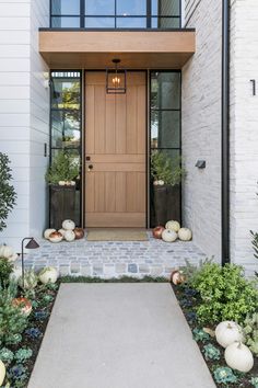 a front door with pumpkins and greenery on the ground in front of it