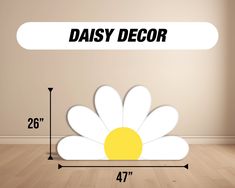 a daisy sitting on top of a wooden floor next to a white sign that says daisy decor