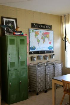 a room with two green lockers and a map on the wall above them in front of a table