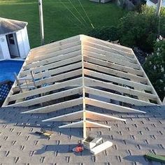 an upside down wooden structure on top of a roof next to a swimming pool in a backyard