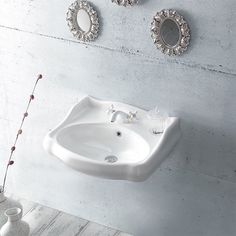 a white sink sitting next to a wall mounted faucet with three mirrors above it