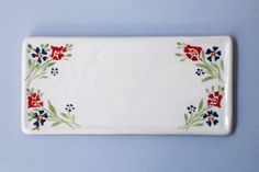 a white plate with red, blue and green flowers on it's edge against a light blue background