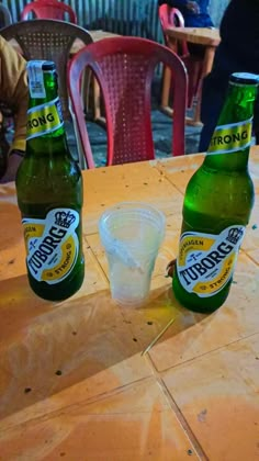 two beer bottles sitting on top of a wooden table