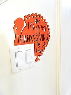 a white light switch sitting next to a happy thanksgiving sign