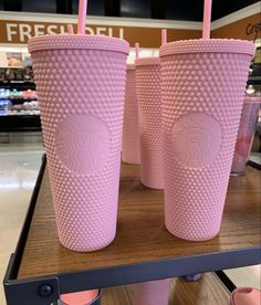 two pink starbucks cups sitting on top of a table