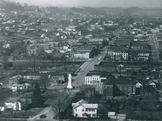 an aerial view of a city with lots of buildings and trees in the foreground