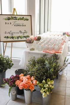 there are many potted plants on the floor next to a sign that says flower bar