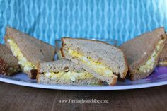 there is a sandwich cut in half on the plate with eggs and cheese inside it