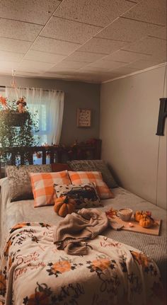 an unmade bed in a small room with pumpkins on the floor and blankets