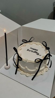 a birthday cake sitting on top of a white box next to a lit candlestick