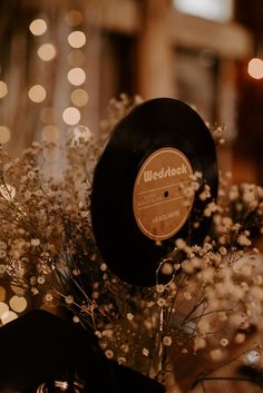 a record sitting on top of a vase filled with flowers and lights in the background