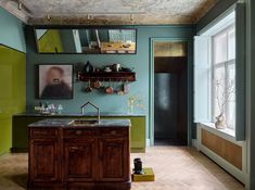 a kitchen with green walls and wooden floors