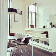 a dining room table and chairs in front of an open kitchen area with wooden floors