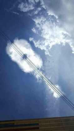 a heart shaped cloud in the sky with power lines above it and a building on the other side