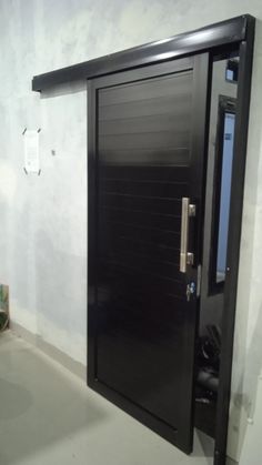 a black door in a white room with a plant on the floor next to it