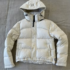 Aritzia Super Puff Shorty In A Size 3xs In Color Matte Pearl. Removable Hood. Thumbholes On Cuff. 2 Exterior Button Pockets And Interior Pocket. Water Repellent. Wind Repellent. 700+ Fill. Brand New. Aritzia Puffers, Winter Coat With Hood, Aritzia Coat Outfit, Aritzia Super Puff High Gloss, White Down Puffer Jacket For Cold Weather, White Down Puffer Jacket For Streetwear, Functional White Puffer Jacket For Fall, White Down Puffer Jacket For Spring, White Sporty Spring Puffer Jacket