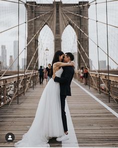 a bride and groom kissing on the brooklyn bridge