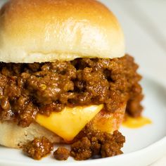 a sloppy joe sandwich on a plate with cheese and chili sauce in the middle, ready to be eaten