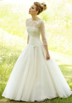 a woman in a white wedding dress standing in the grass