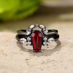 a close up of a ring with a red stone in the middle and white stones around it