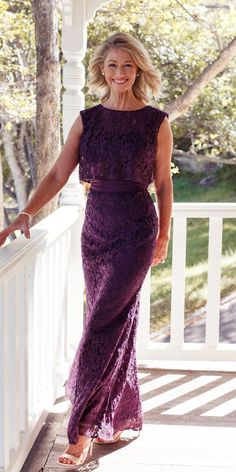 a woman in a purple dress standing on a porch with her hand on the railing