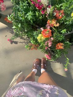 a person laying on the ground with their feet up next to a flower pot full of flowers