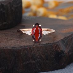 a red and white diamond ring sitting on top of a piece of wood