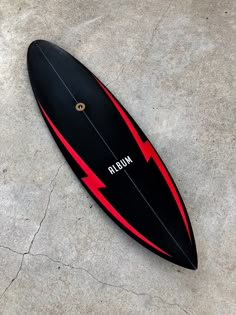 a black and red surfboard laying on the ground